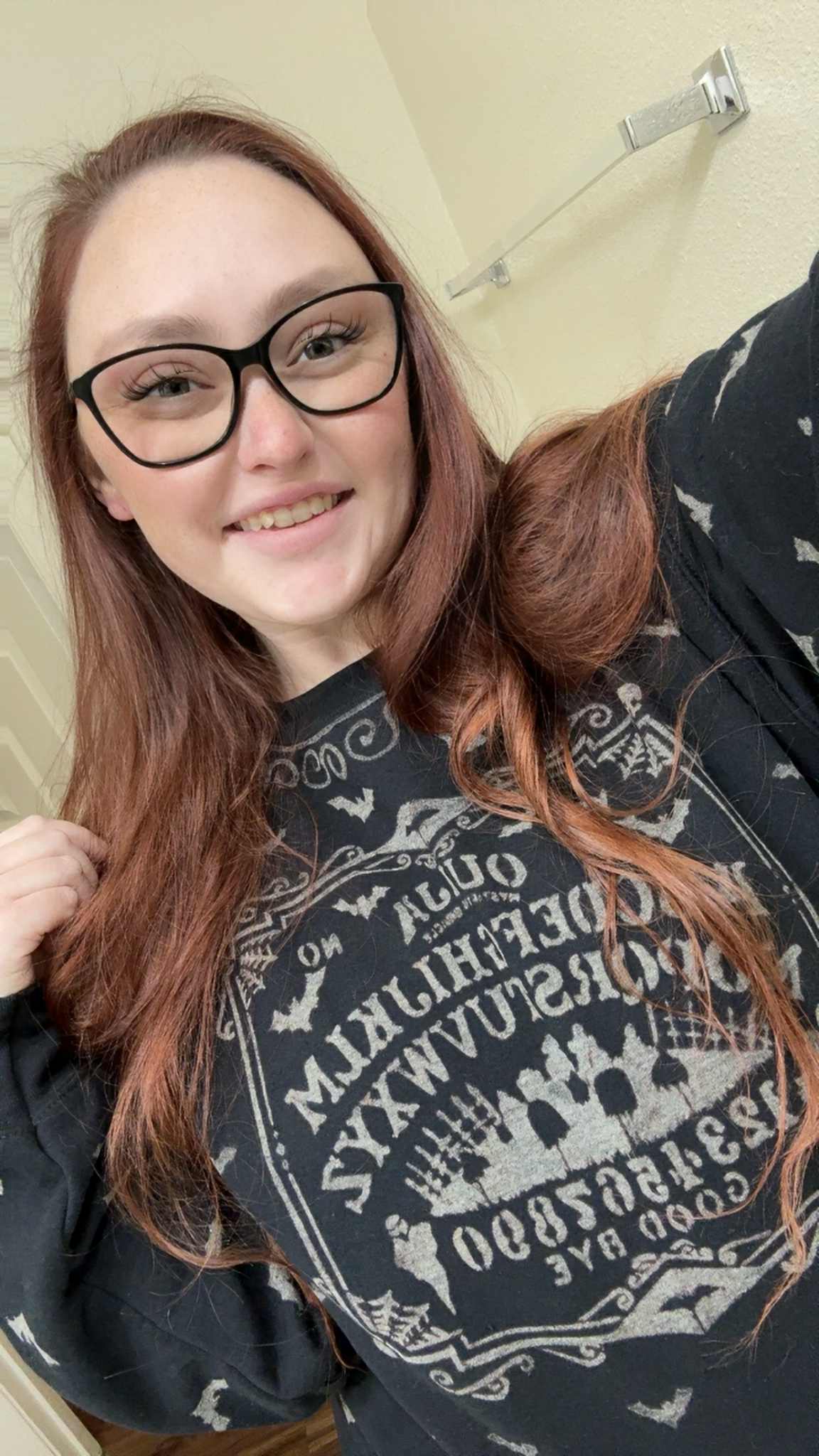 The owner Keri wearing a dark sweater with a pattern, standing against a neutral background.